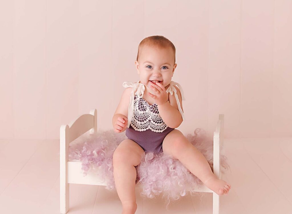 baby sitting on a bed, milestone session